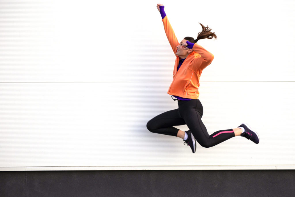 Young woman exercise and jump on street with white background
